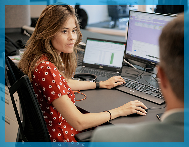 Account Managerin am Computer im Gespräch mit Kollegen